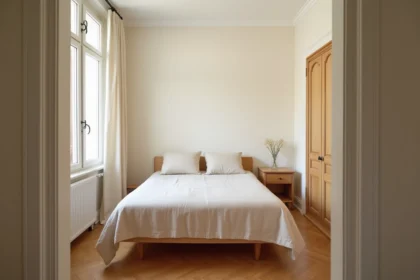 Chambre standard française d'environ 12 m² avec lit double, parquet en bois et rangements compacts illustrant les dimensions réglementaires