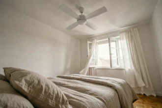 Ventilateur de plafond silencieux au-dessus d'un lit cosy dans une chambre minimaliste et reposante