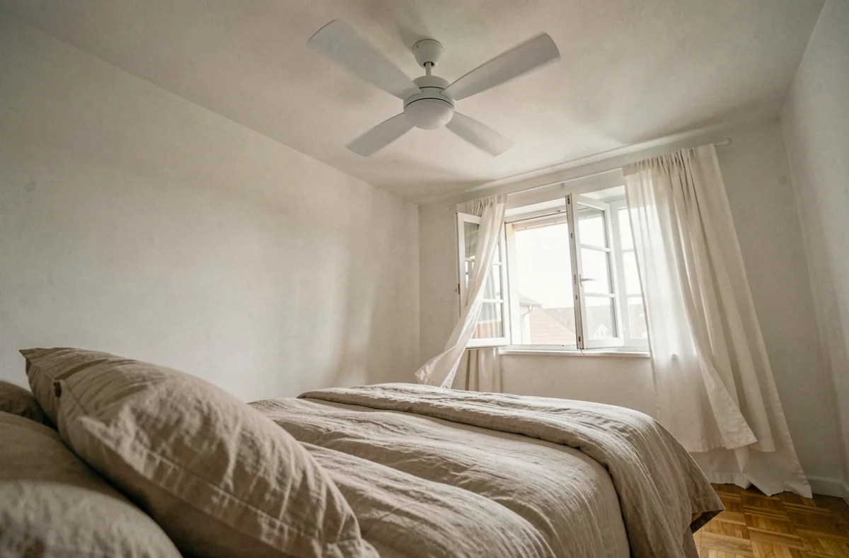 Ventilateur de plafond silencieux au-dessus d'un lit cosy dans une chambre minimaliste et reposante